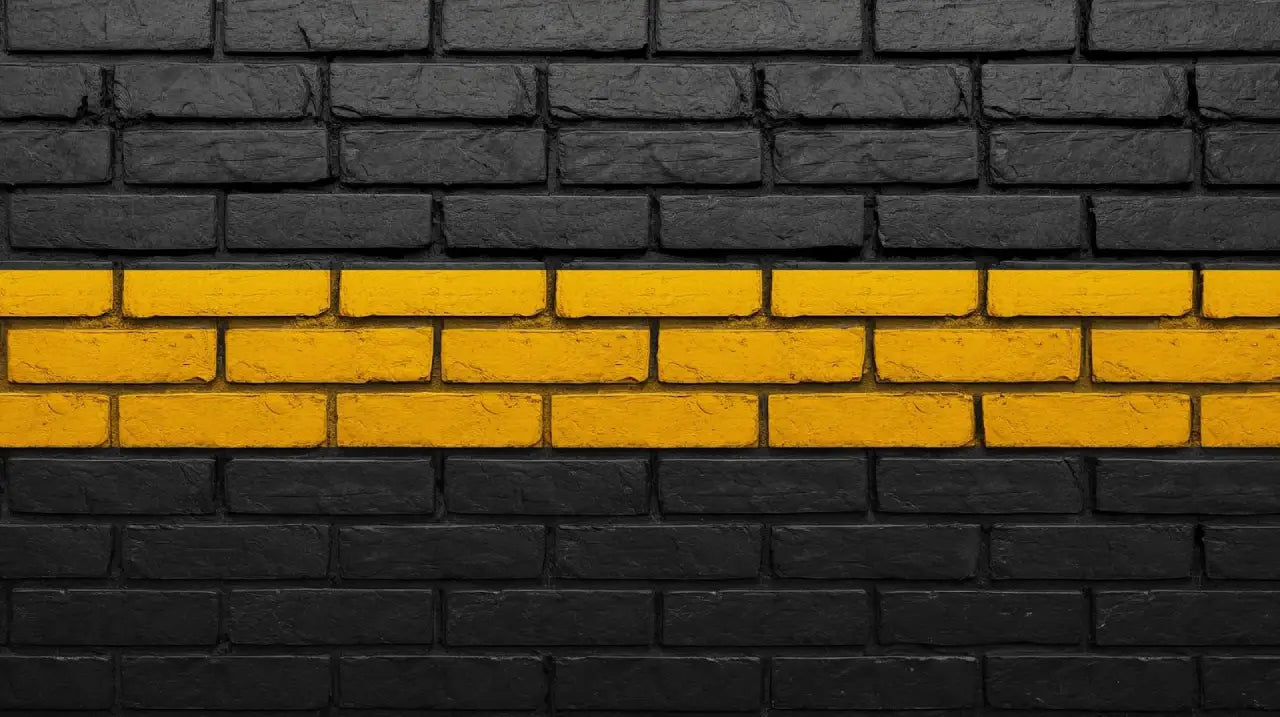 Black painted brick wall with two horizontal yellow painted brick stripes across the middle.